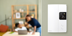 An installed smart thermostat in the foreground with family relaxing in the background. An installed smart thermostat in the foreground with family relaxing in the background.