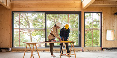 Construction workers review plans inside a partially constructed building. Construction workers review plans inside a partially constructed building.
