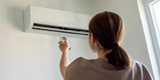 Woman in apartment adjusting heat pump Woman in apartment adjusting heat pump