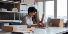 Woman logging product information on laptop in office Woman logging product information on laptop in office