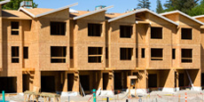A construction site featuring a row of partially built townhouses with wooden frames. A construction site featuring a row of partially built townhouses with wooden frames.