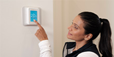Person adjusting programmable thermostat Person adjusting programmable thermostat