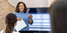 Female manager uses large screen to present spreadsheet