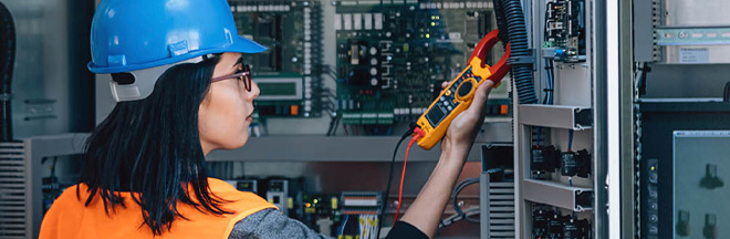 Young maintenance engineer testing voltage with digital multimeter.