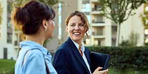 A female homeowner consults a tablet held by a technician, discussing the settings of an external heat pump unit. A female homeowner consults a tablet held by a technician, discussing the settings of an external heat pump unit.