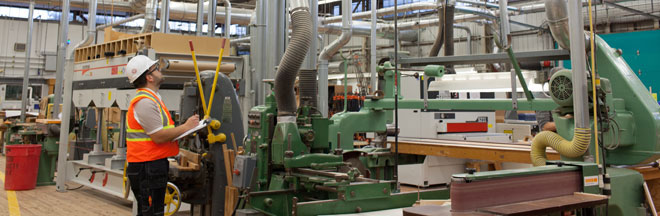 An engineer inspects fan/exhaust hoses in an industrial facility.