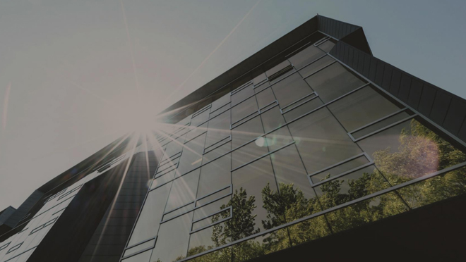 A modern, commercial building with a glass exterior viewed from the ground upwards