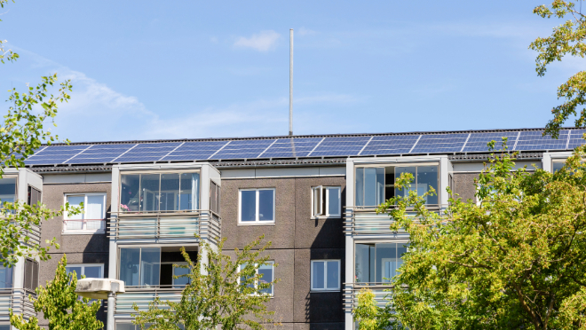 A solar panel array on the roof of a building with the sky in the background