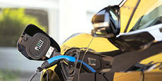 Electric car with plug-in socket at charge station charging battery