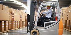 Worker driving an electric forklift in a warehouse.