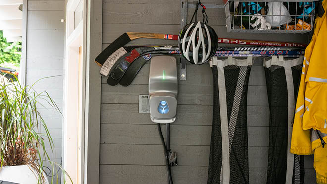 An illuminated EV charger inside a home garage.