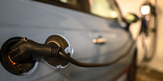 Electric car charging with close-up of plugged charging cable. Charging station blurred in background. Electric car charging with close-up of plugged charging cable. Charging station blurred in background.