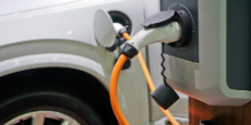 An electric vehicle is plugged in at a charging station in a parking lot.