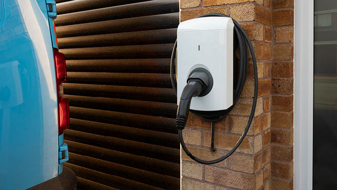 Electric car charging point attached to a stone wall.