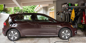 Maroon electric car connected to a home EV charger.