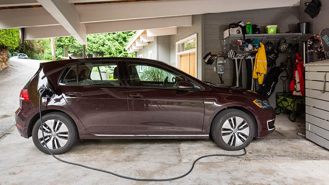 Maroon electric car connected to a home EV charger.