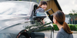 Mother charging the electric car and the kid inside the car.