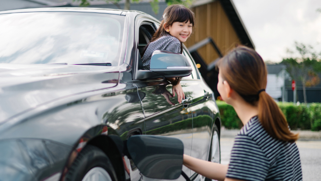 Mother charging the electric car and the kid inside the car.