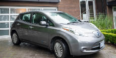 Nissan Leaf electric car parked in front of a closed garage.