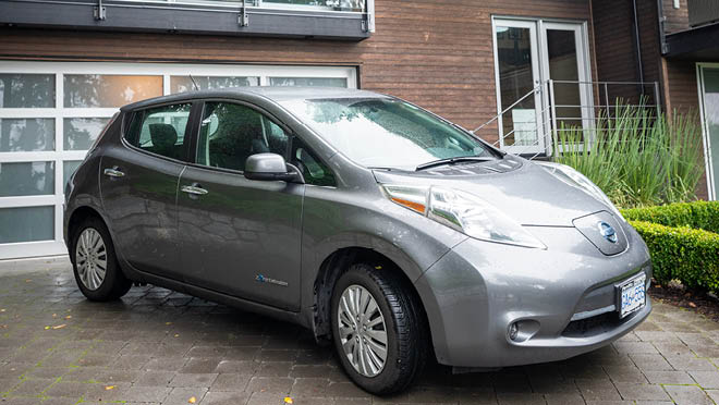 Nissan Leaf electric car parked in front of a closed garage.