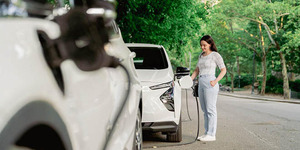 Person charging electric car in park in New York.