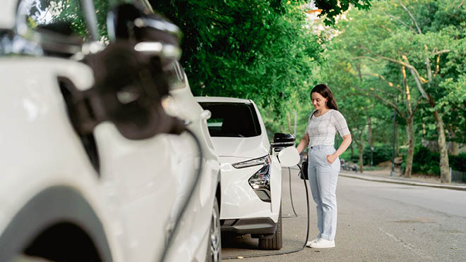 Person charging electric car in park in New York.