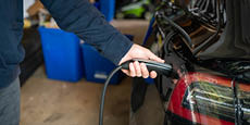 A side view close up shot of a person plugging cable in electric car.