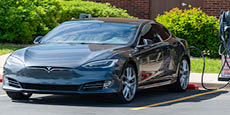 Tesla electric car charging in a parking lot.