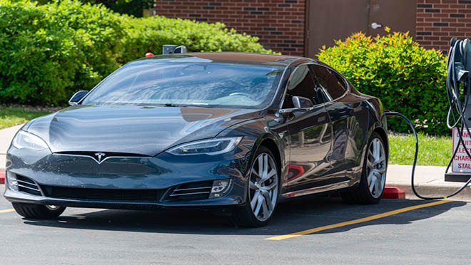 Tesla electric car charging in a parking lot.