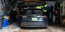 A black Tesla EV charging inside a home garage.