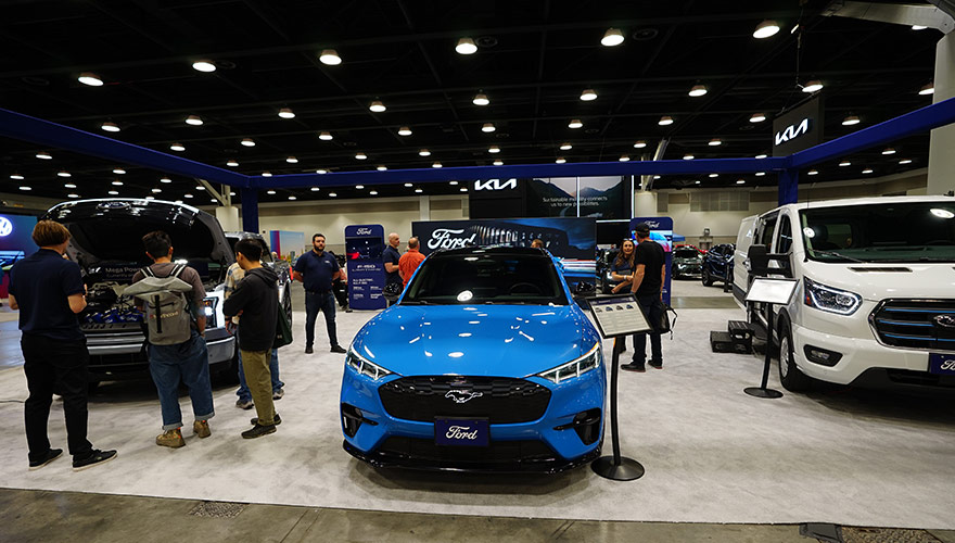 Various electric vehicles on display at last year's Everything Electric show in Vancouver. Featured in the center is a blue Ford Mach-E electric SUV.