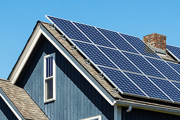 Solar panels cover an entire roof of a blue house